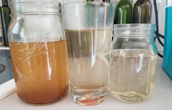 Another reviewer photo of different glasses of water that range from dirty to cleaner after using K-cup cleaner