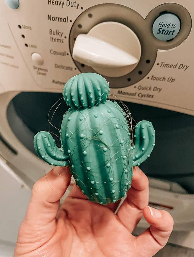 Reviewer holding silicone cactus that has a lot of hair caught on it 