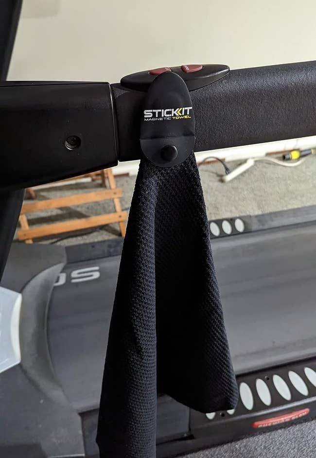 reviewer photo of the black towel hanging from a treadmill by the magnet