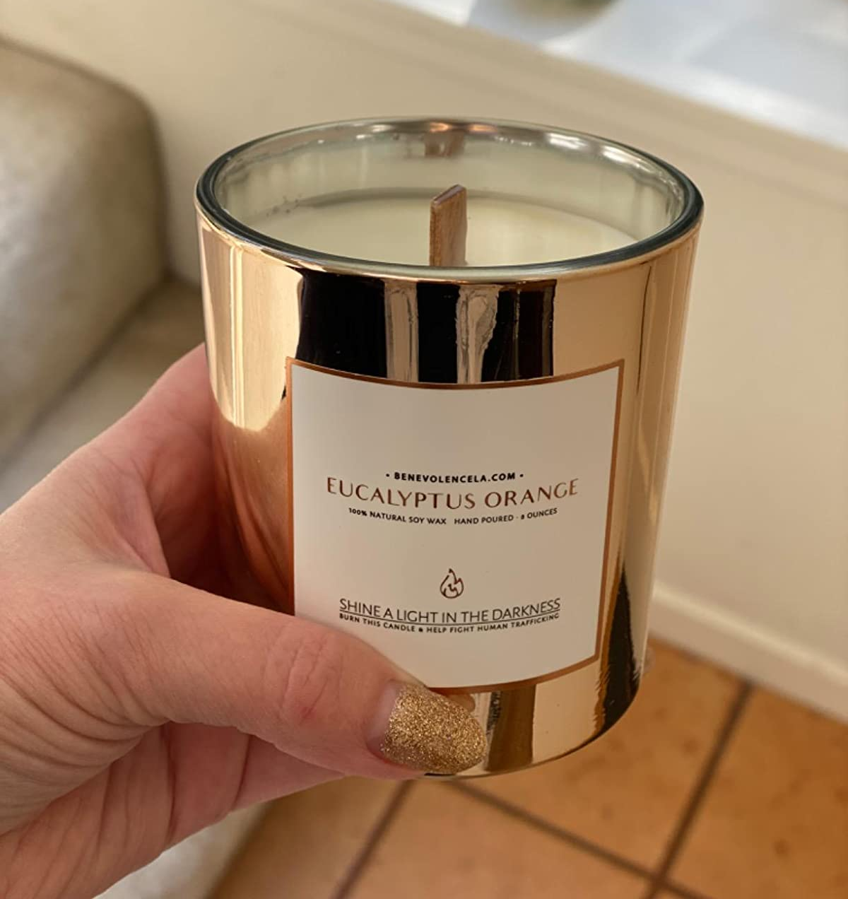 Reviewer holding candle in gold jar with woodwick unlit