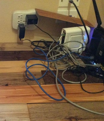reviewer's photo of their WiFi modem and haphazard wires bundled together