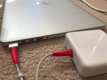 reviewer's red sugru strengthening mac charger cables where the wires meet the magsafe plug and the brick part