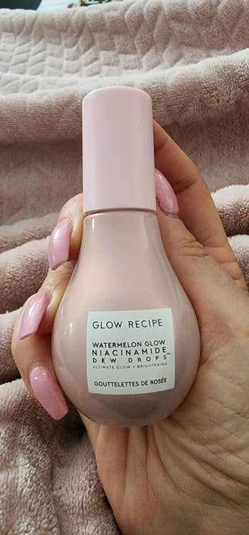 Hand holding a bottle of Glow Recipe Watermelon Glow Niacinamide Dew Drops skincare product