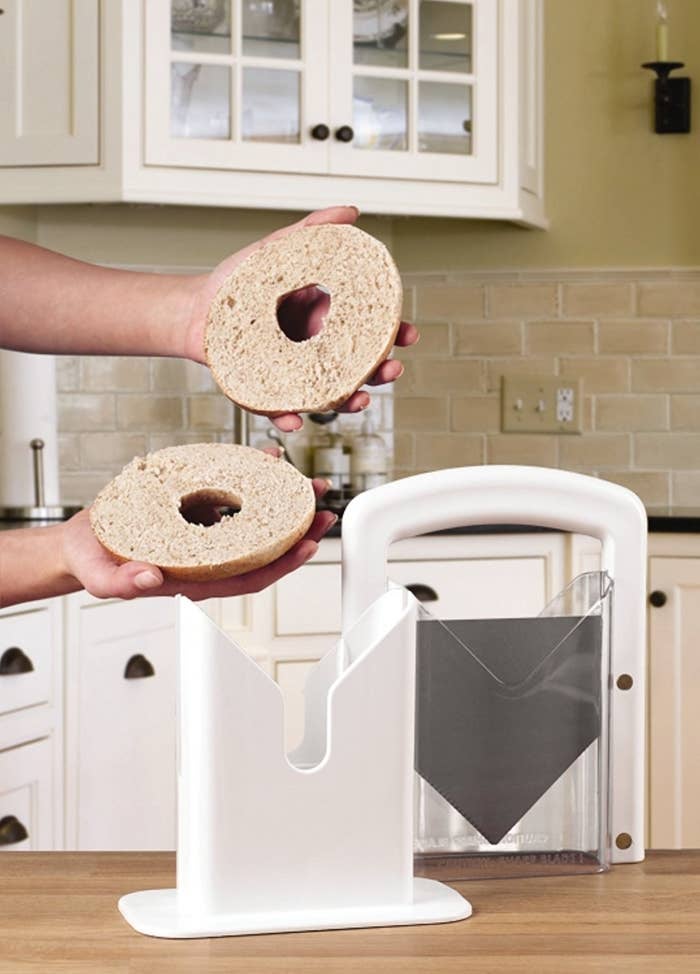 person holding bagel in half that was cut with bagel slicer