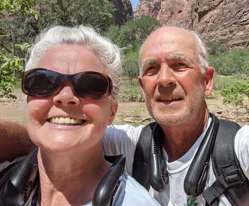 An older mates wearing the fans astir their necks smiling and posing outdoors successful a rocky upland area
