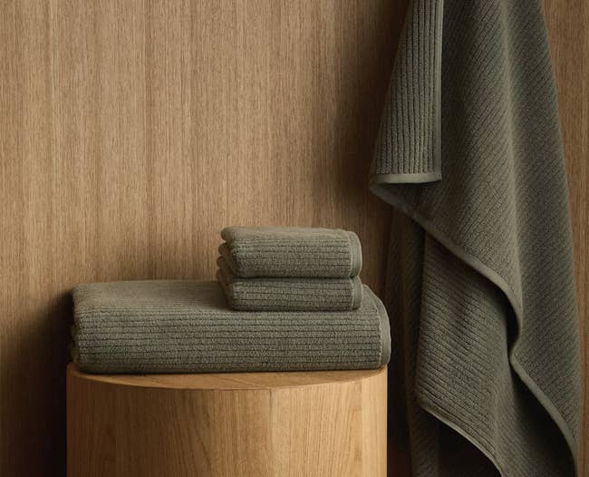 Stacked bath towels connected a woody aboveground with 1 towel hanging