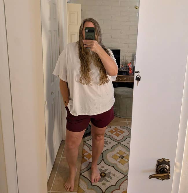 Person taking a reflector selfie wearing a escaped achromatic apical and shorts, lasting successful a country with a rug and disposable door