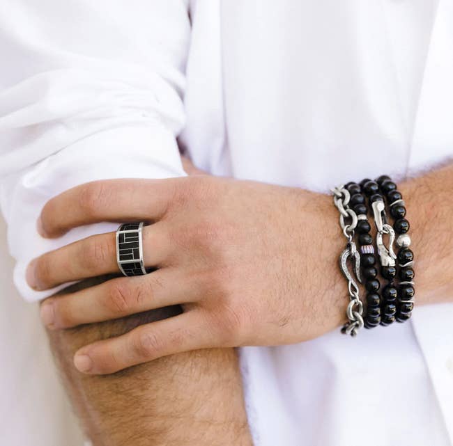 person wearing stacked onyx beaded bracelets