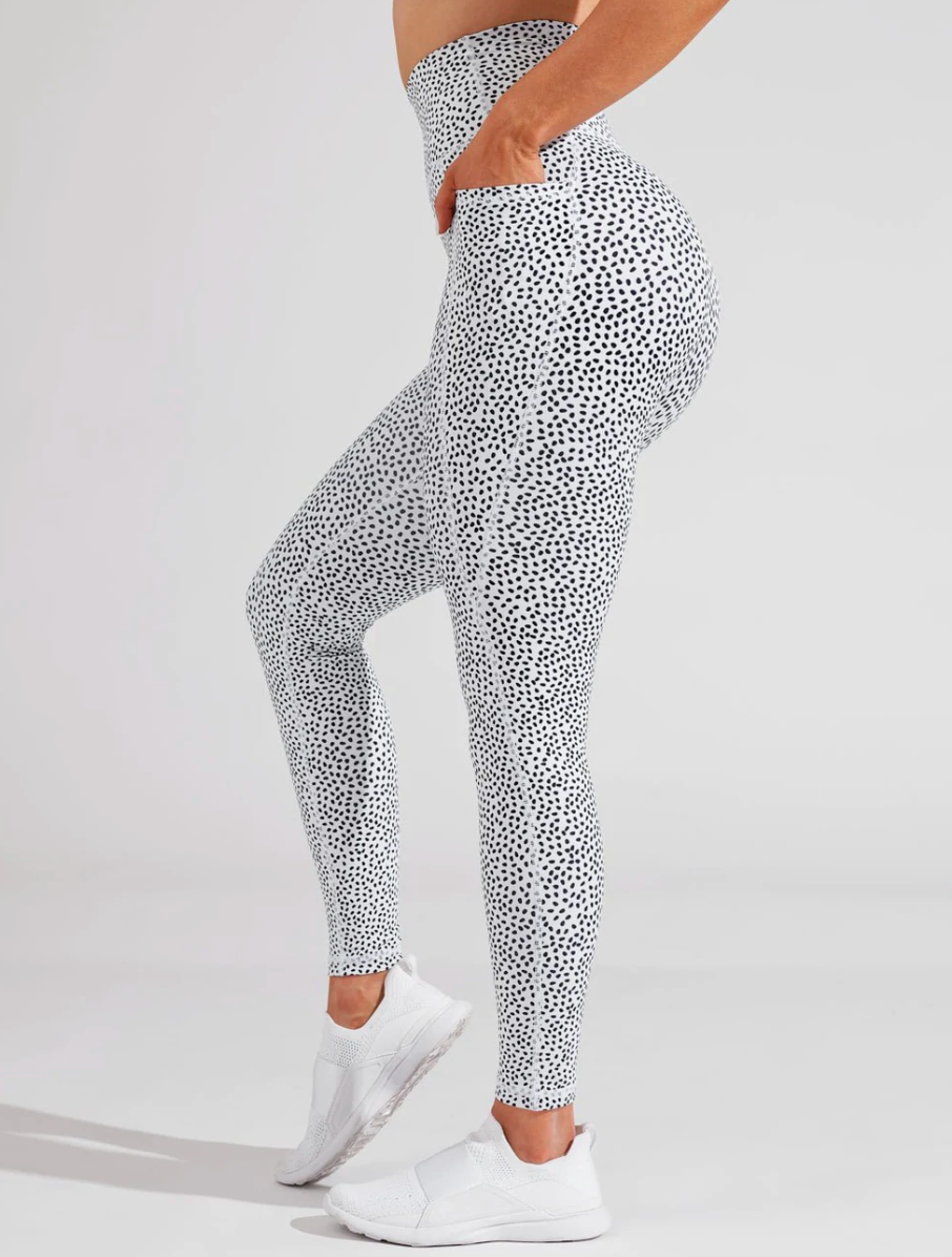 Model is wearing white leggings with black speckled dots throughout