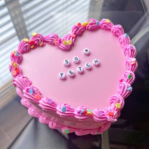 A pink heart-shaped faux-cake jewelry box lined with fake pink icing and sprinkles, with 