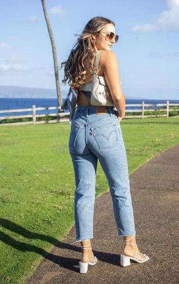 a reviewer poses in the jeans with heels