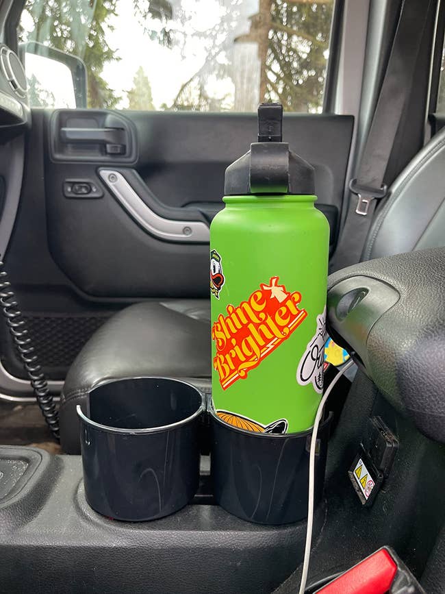 a reviewer's bright green water bottle in the attachment in their cupholder