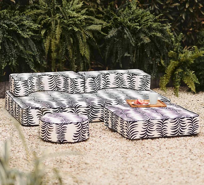 Patterned outdoor sectional with cushions and a tray with items on it