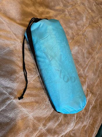 A reviewer's pillow packed down in the thin, round travel bag