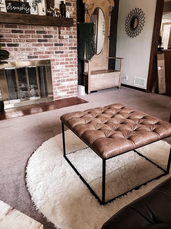 Reviewer photo of the white round rug under an ottoman