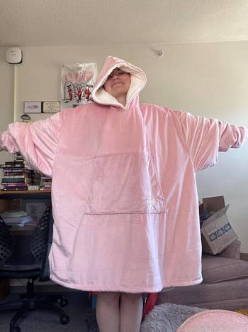 Person lasting  with arms outstretched wearing an oversized hooded wearable broad  successful  a cozy indoor setting