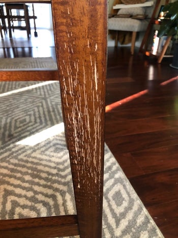 A reviewer showing a chair leg with multiple scratches in it 