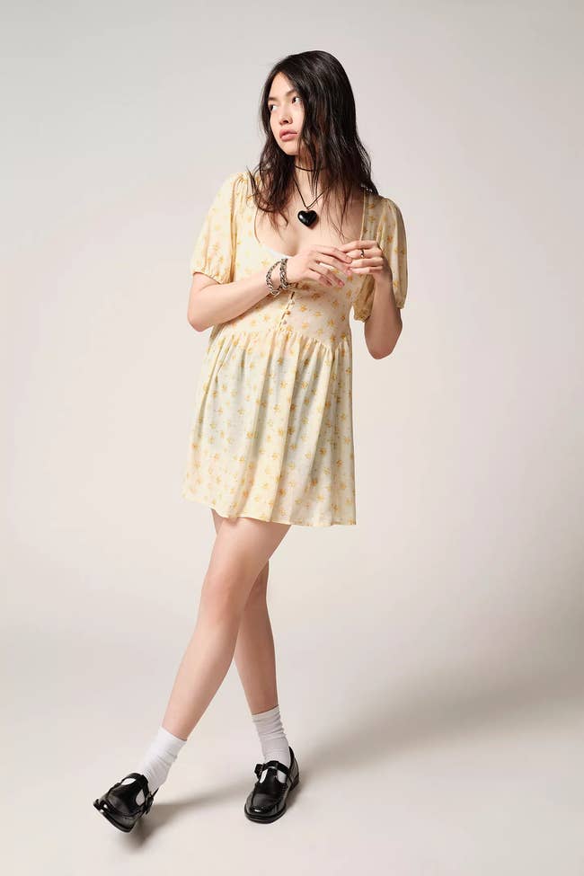 a model in a yellow babydoll dress with flowers on it