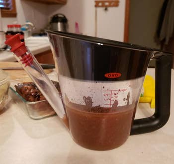 reviewer photo of the fat separator holding gravy juices, with a distinct layer of fat floating at the top