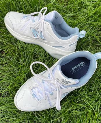reviewer photo of the white and blue sneakers on a patch of grass