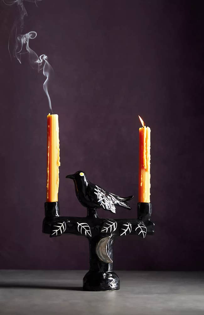 the black candelabra with a raven in the center and two orange candles in the holders