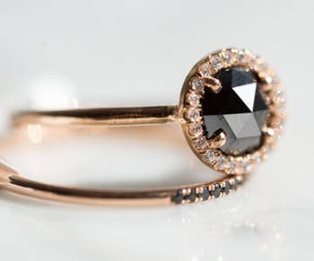 a round engagement ring with a black diamond in the middle and a halo of diamonds around it