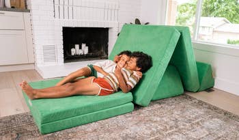 two kids laying on a green nugget couch
