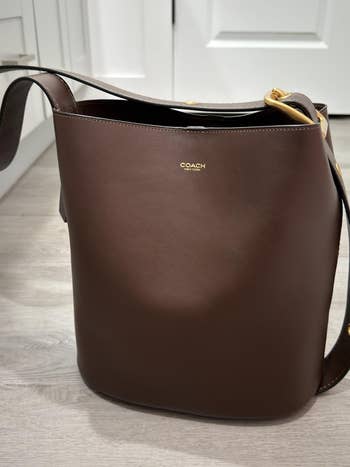 Coach brownish  leather enarthrosis  container  with golden  details, featuring a sleek plan  perfect  for mundane  use