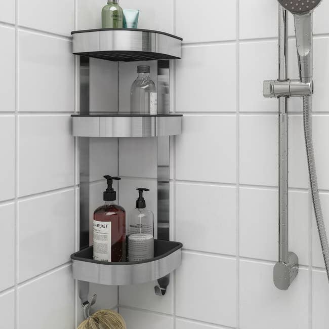 Stainless alloy  ablution  caddy with 3  shelves holding toiletries, mounted connected  achromatic  tiled ablution  partition  with a detachable showerhead