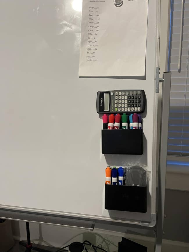 A whiteboard with a calculator and colorful markers successful  holders. A expanse  with mathematical formulas is attached above