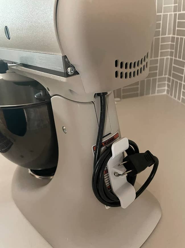 reviewer image of a white cord organizer on the back of a stand mixer