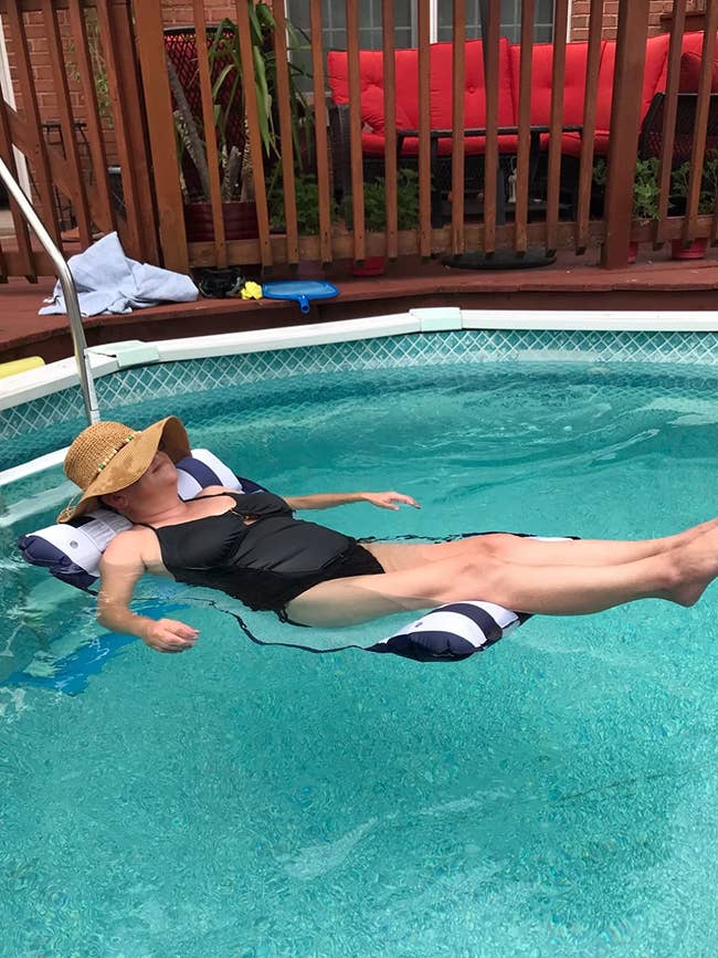 A reviewer lounging on the striped hammock in a pool