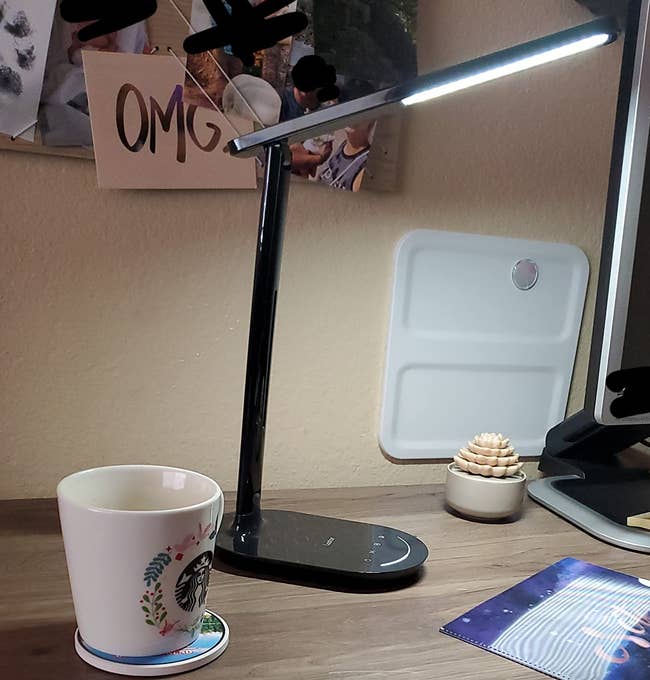 a reviewer photo of the illuminated light sitting on a desk 