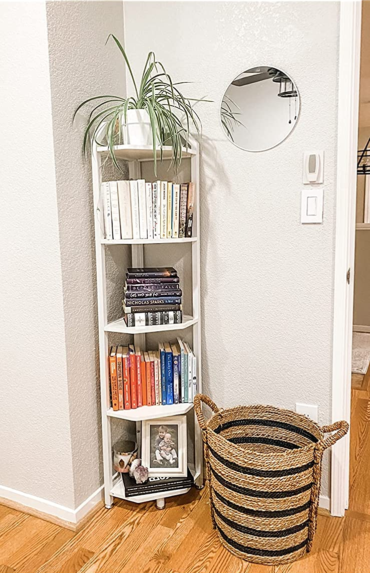 Reviewer image of white corner bookshelf with books and photos on each tier