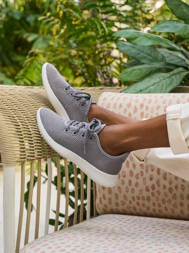 Person relaxing connected a woven chair, wearing casual grey knit sneakers