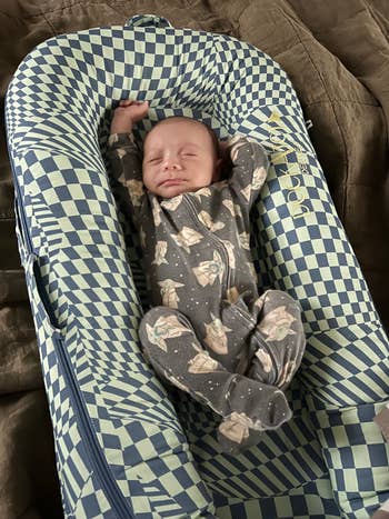 a baby in a blue checker print dockatot