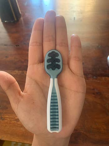 image of small blue silicone spoon in the palm of a reviewer's hand