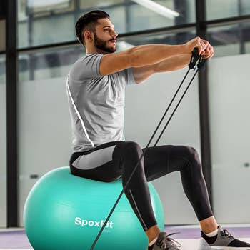 model sitting on green exercise ball with armbands attached to it