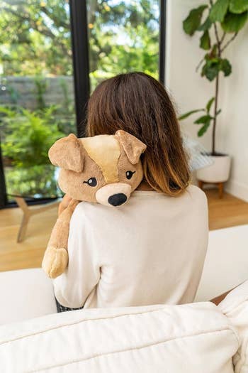 Person sitting, holding a weighted plush dog toy