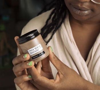 Model holding tin of face scrub