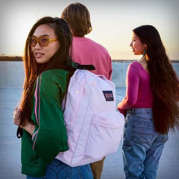 Three people stand outdoors; one wears sunglasses and a backpack. They have casual attire. The scene suggests a focus on stylish, everyday products