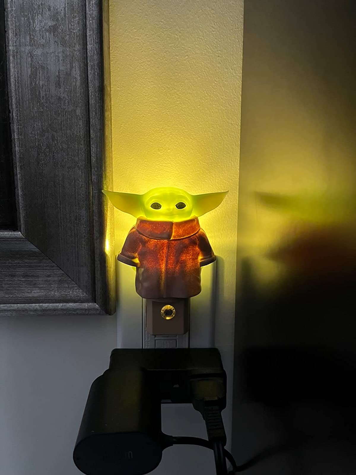 Reviewer's Baby Yoda nightlight lit up in the dark