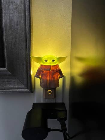 Reviewer's Baby Yoda nightlight lit up in the dark