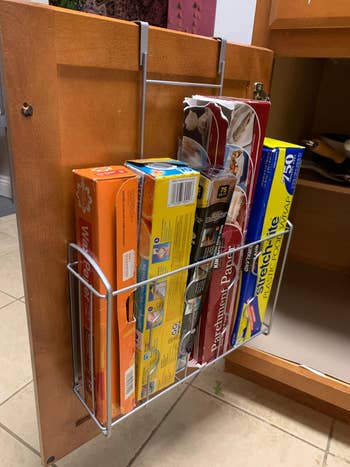 Cabinet doorway organizer holding wax paper, aluminum foil, and integrative wrapper successful a room setting