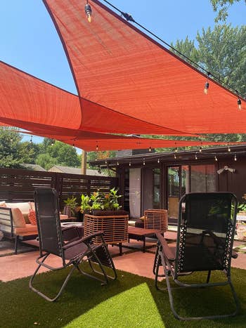 Outdoor patio with lounge chairs, reddish sunshade canopy, and cozy seating area, perfect for relaxation and entertaining successful a plot setting