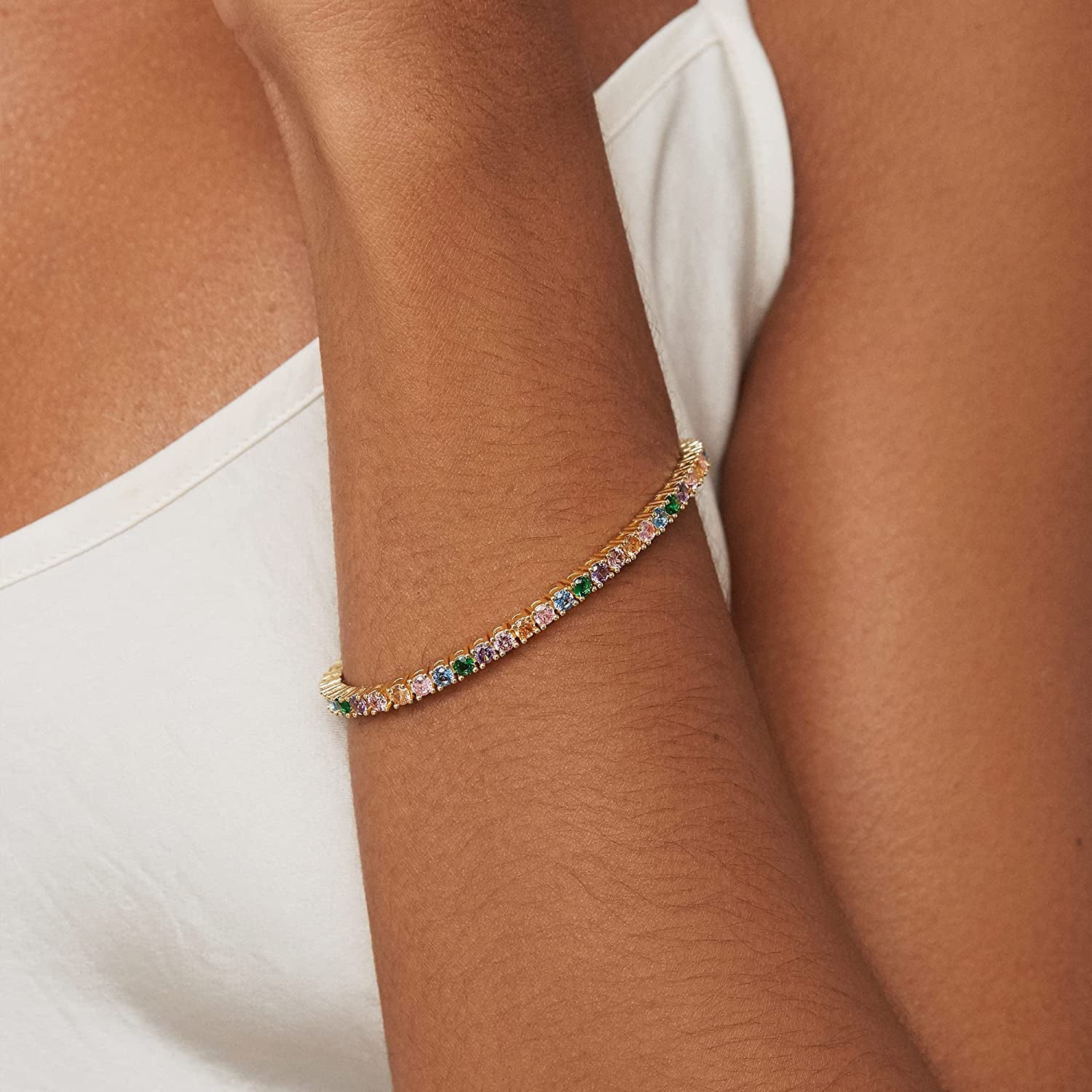 Model in gold tennis bracelet with pastel gems 