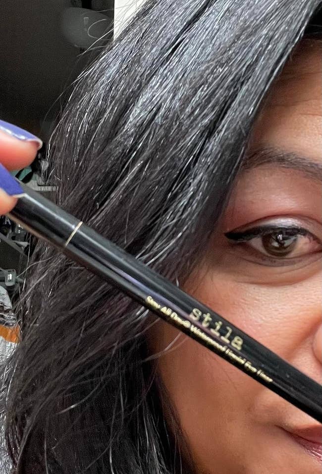 reviewer holding the eyeliner and showing how it looks on their eye