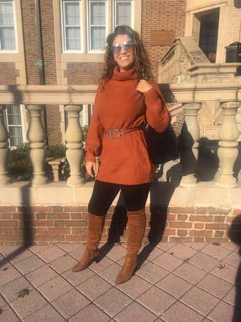 Person successful a turtleneck sweater formal with belt, leggings, knee-high boots, and sunglasses, lasting outdoors adjacent a building