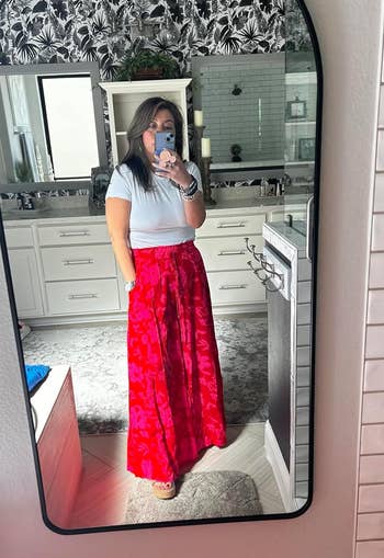 reviewer wearing the pants in red and pink floral print with white short sleeve top