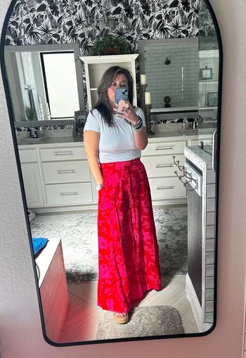 reviewer wearing the pants in red and pink floral print with white short sleeve top